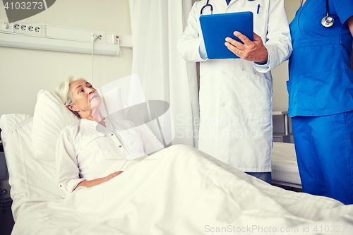 Image of doctor and nurse visiting senior woman at hospital