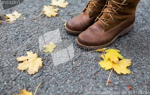 Image of female feet in boots and autumn leaves