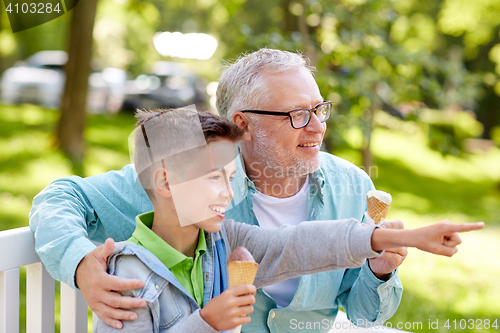 Image of old man and boy eating ice cream at summer park