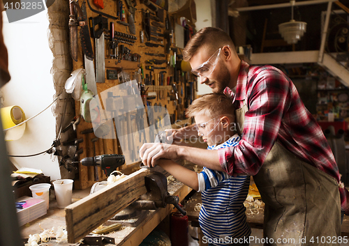 Image of father and son with plane shaving wood at workshop