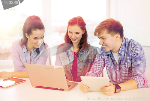 Image of three smiling students with laptop and tablet pc