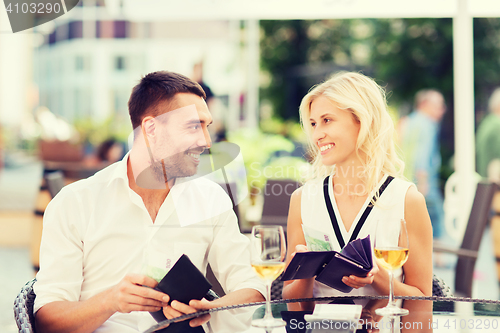 Image of happy couple with wallet paying bill at restaurant