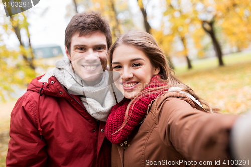 Image of happy young couple taking selfie in autumn park