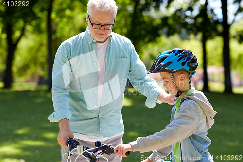 Image of grandfather and boy with bicycle at summer park