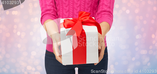 Image of close up of woman in pink sweater holding gift box