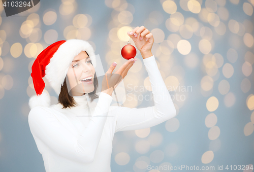 Image of happy woman in santa hat with christmas ball