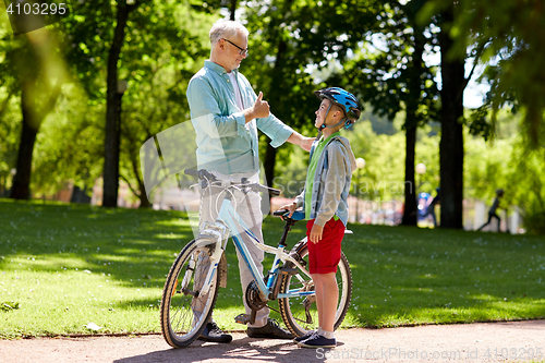 Image of grandfather and boy with bicycle at summer park