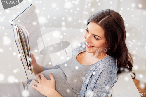 Image of happy pregnant woman reading book at home