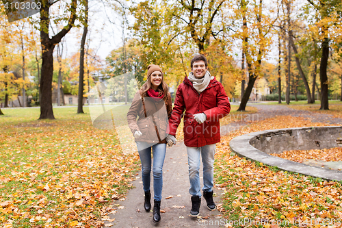 Image of happy young couple running in autumn park