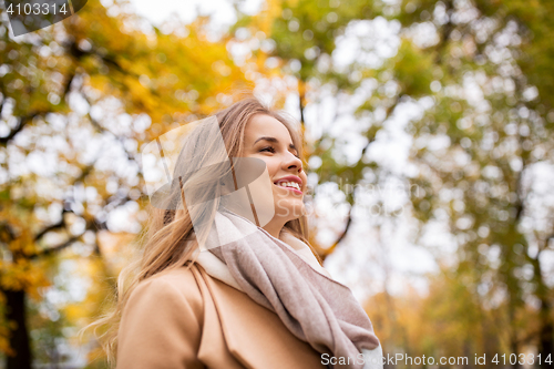 Image of beautiful happy young woman walking in autumn park