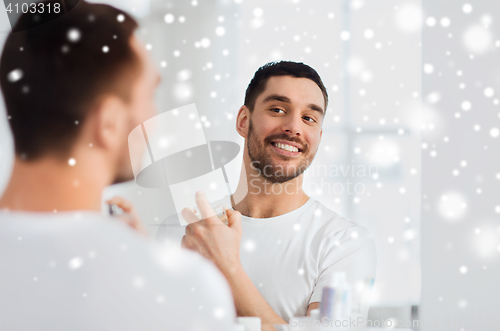 Image of man with perfume looking to mirror at bathroom