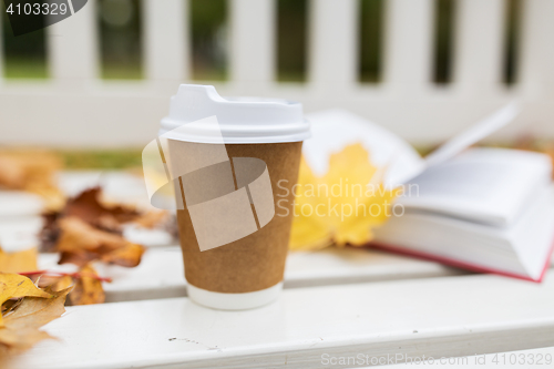 Image of coffee drink in paper cup on bench at autumn park