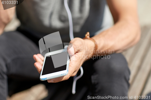Image of close up of man with smartphone and earphones wire