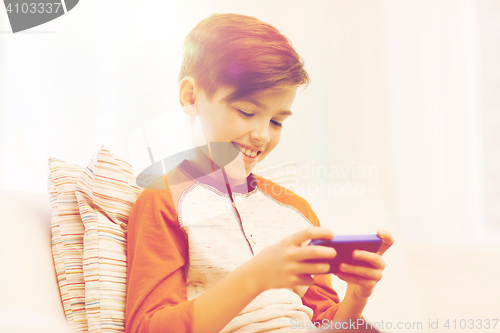 Image of boy with smartphone texting or playing at home