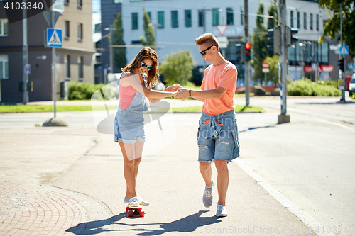 Image of teenage couple riding skateboards on city street