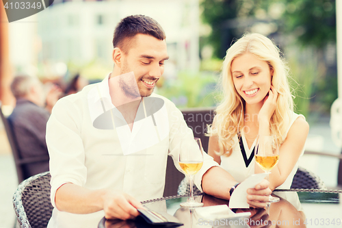 Image of happy couple with wallet and bill at restaurant