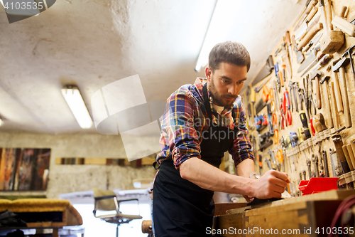 Image of carpenter working with plane and wood at workshop