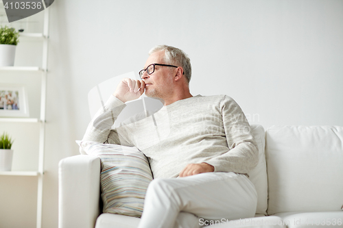 Image of  senior man sitting on sofa at home and thinking