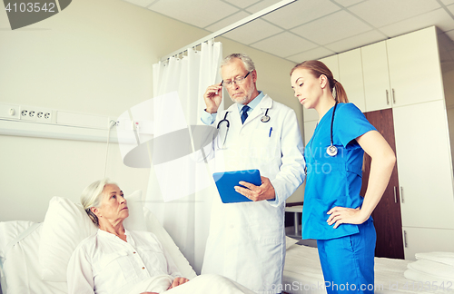 Image of doctor and nurse visiting senior woman at hospital