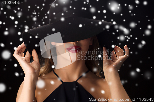 Image of beautiful woman in black hat over snow