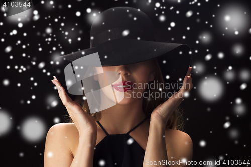 Image of beautiful woman in black hat over snow