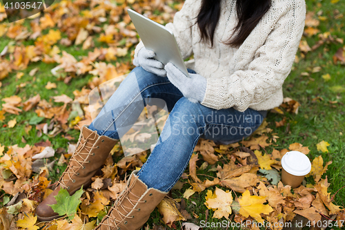 Image of woman with tablet pc and coffee in autumn park