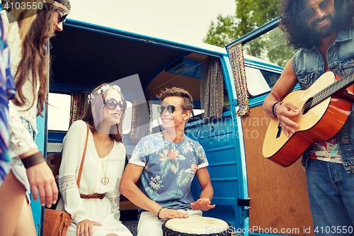 Image of happy hippie friends playing music over minivan