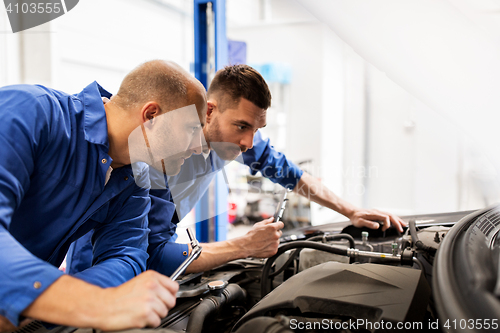 Image of mechanic men with wrench repairing car at workshop