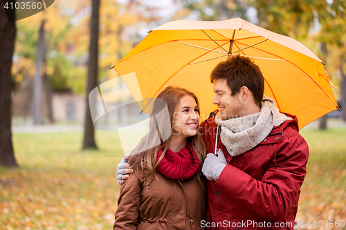 Image of smiling couple with umbrella in autumn park