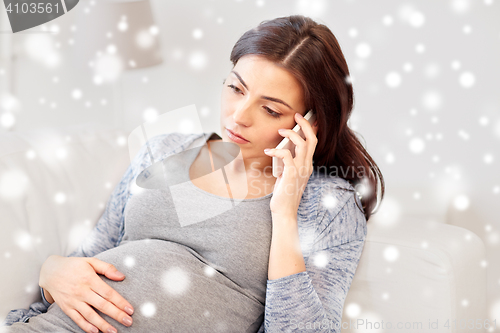 Image of sad pregnant woman calling on smartphone at home