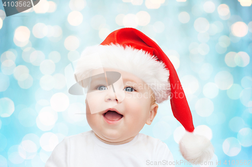 Image of baby boy in christmas santa hat over blue lights