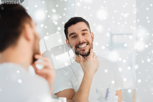 Image of happy young man looking to mirror at home bathroom