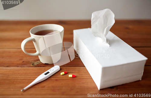 Image of cup of tea, paper wipes and thermometer with pills