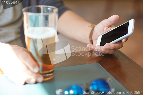 Image of close up of man with smartphone and beer at pub