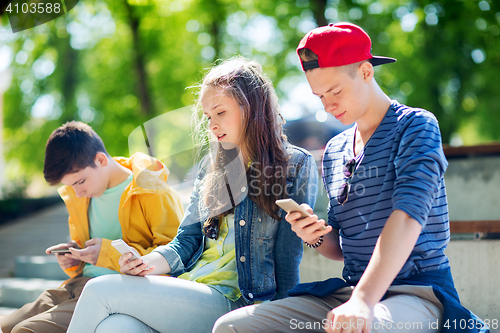Image of teenage friends with smartphones outdoors