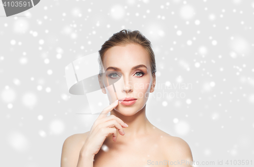 Image of beautiful young woman showing her lips over snow