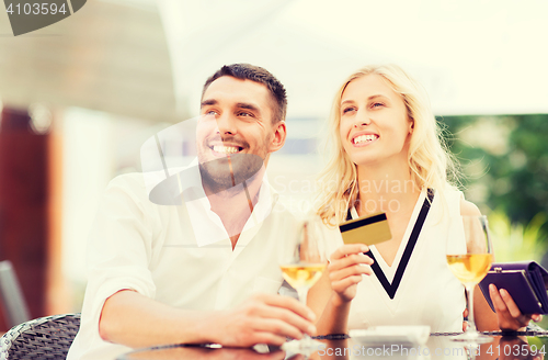 Image of happy couple with bank card and bill at restaurant