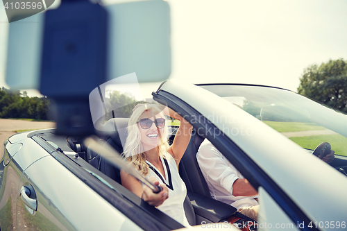 Image of happy couple in car taking selfie with smartphone