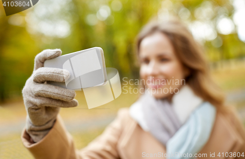 Image of woman taking selfie by smartphone in autumn park