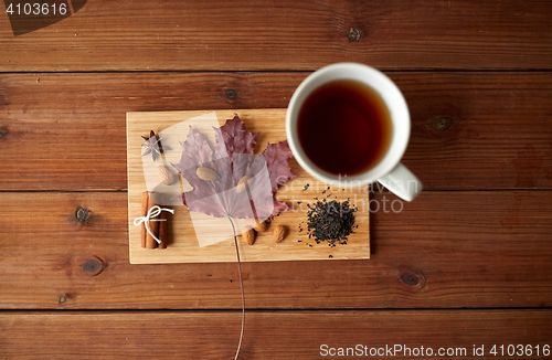 Image of cup of tea, maple leaf and almond on wooden board