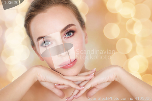 Image of beautiful young woman face and hands over lights