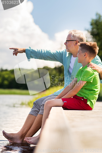 Image of grandfather and grandson sitting on river berth