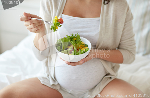 Image of close up of pregnant woman eating salad at home