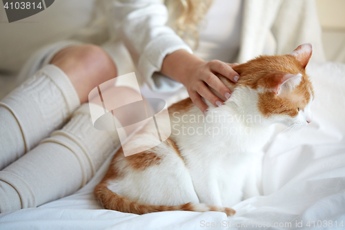 Image of happy young woman with cat in bed at home