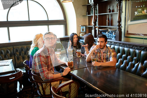 Image of friends with beer watching football at bar or pub