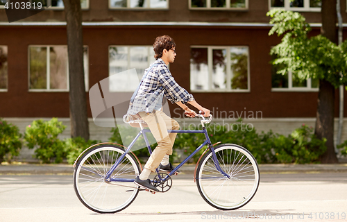 Image of young hipster man with bag riding fixed gear bike