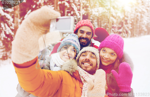 Image of smiling friends with camera in winter forest