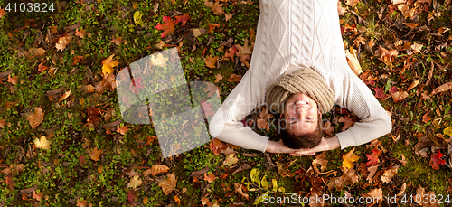 Image of smiling young man lying on ground in autumn park