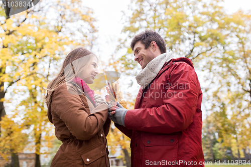 Image of happy couple with maple leaves in autumn park