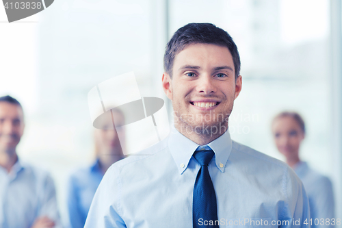 Image of smiling businessman with colleagues in office